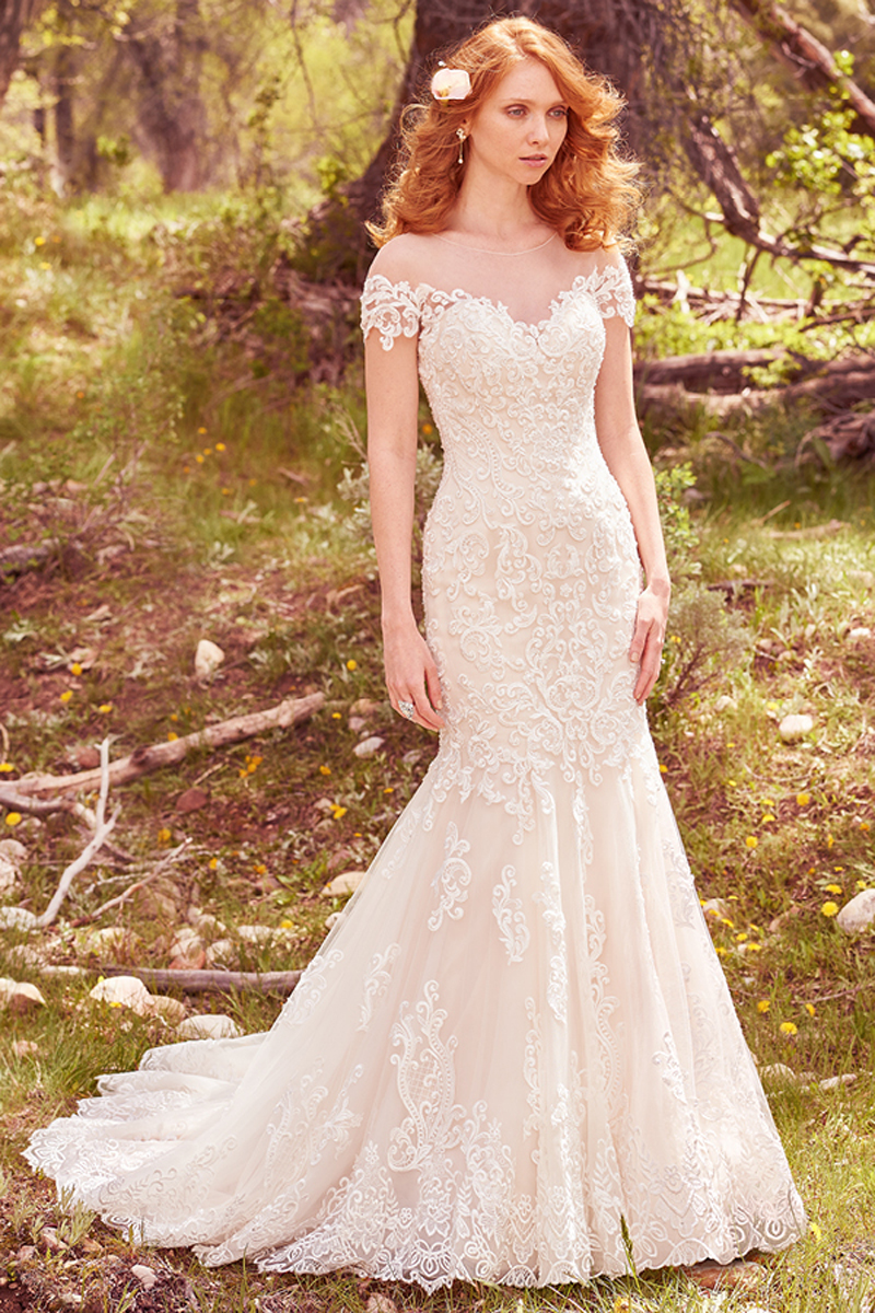 This romantic fit-and-flare features cascades of lace appliqués that trim the illusion sweetheart neckline, illusion off-the-shoulder sleeves, and illusion low back with keyhole opening. Complete with exquisite hemline of lace appliqués. Finished with covered buttons over zipper closure. 
<a href="https://www.maggiesottero.com/maggie-sottero/marcy/10122?utm_source=mywedding.com&amp;utm_campaign=spring17&amp;utm_medium=gallery" target="_blank">Maggie Sottero</a>