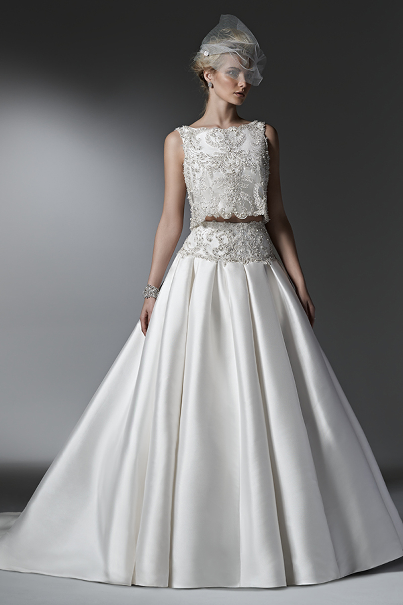 Luxuoso e totalmente de cortar a respiração, este vestido com efeito balão de duas pessoas corresponde ao auge do glamopur com um saia volumosa Mikado Vizela com bolsos laterais. As baínhas da renda apresentam cristais Swarovski. Decote barco e um fecho.
<a href="https://www.maggiesottero.com/sottero-and-midgley/dharma/9559" target="_blank">Sottero and Midgley</a>