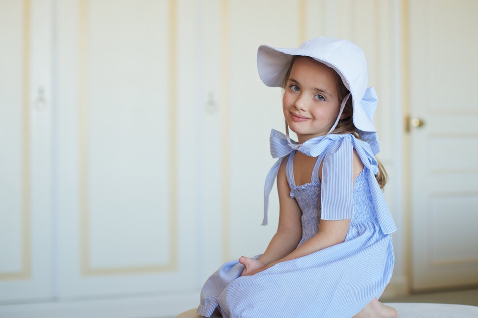 menina vestido azul de alças chapéu com um grande laço