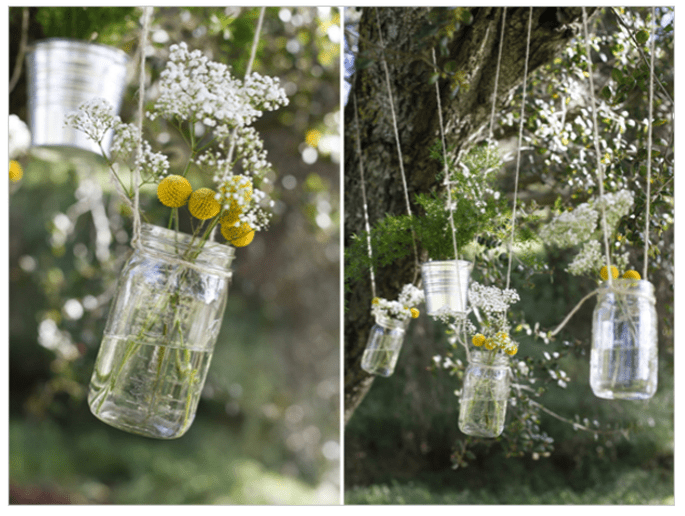 Frascos de cristal com flores pendurados em ramas de árvore. 