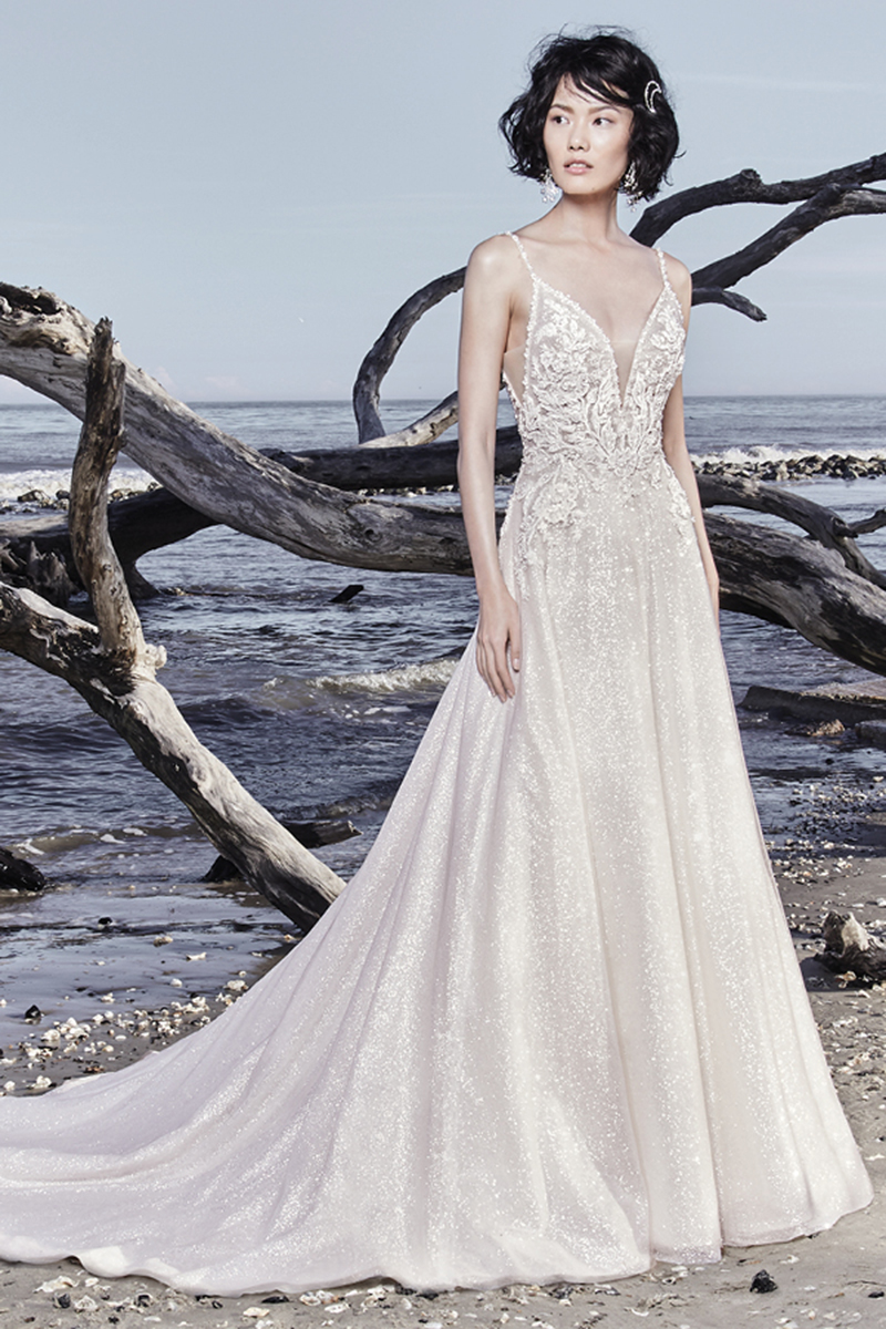 Este maravilhoso vestido de noiva linha-A é confecionado com um tule brilhante que exibe pormenores rendados de renda que conferem um toque muito sensual. Alças finas terminam o decote em forma de V, quer à frente como atrás. Terminado com botões que cobrem o fecho.
<a href="https://www.maggiesottero.com/sottero-and-midgley/chad/11528">Sottero and Midgley</a>