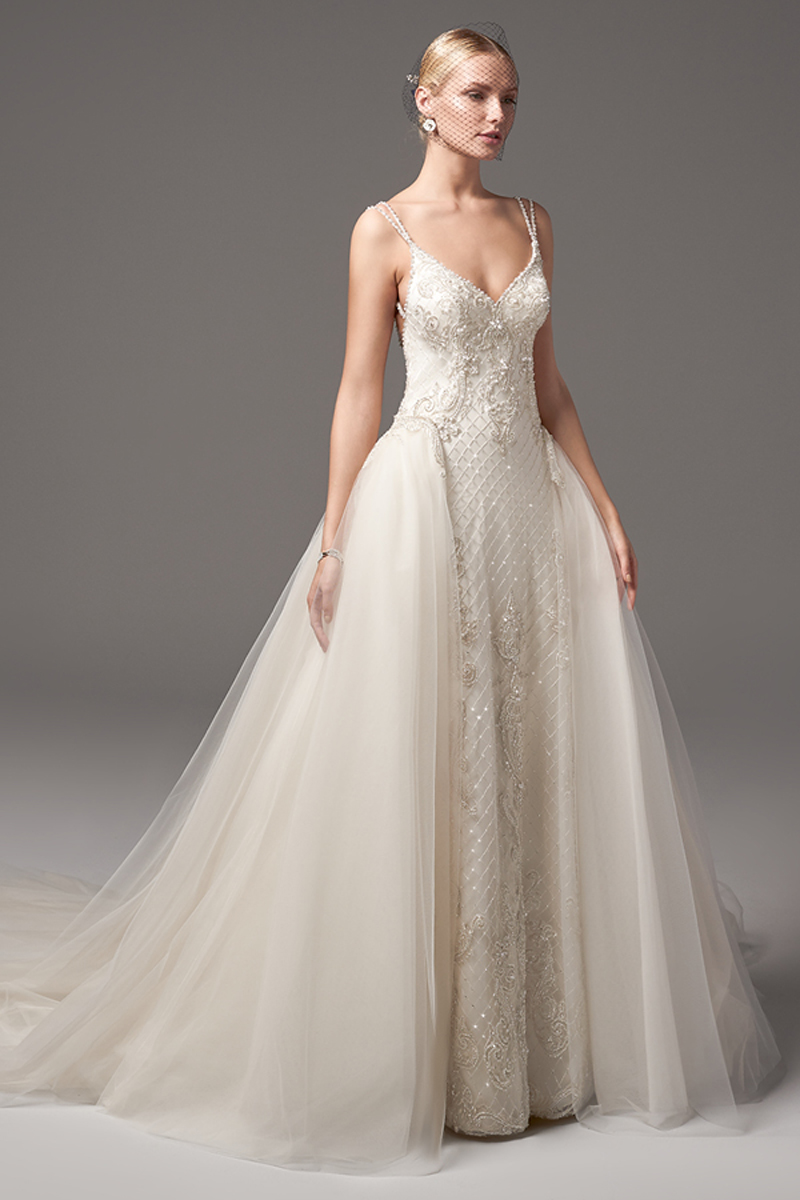 Este magnífico vestido apresenta contas em renda ao longo de costuras e bainhas cruzadas deslumbrantes. Alças duplas com cristais Swarovski que completa o decote em V e as costas abertas. Terminado com botões de pérolas em vez do fecho.
<a href="https://www.maggiesottero.com/sottero-and-midgley/miles/10242?utm_source=mywedding.com&utm_campaign=spring17&utm_medium=gallery" target="_blank">Sottero and Midgley</a>