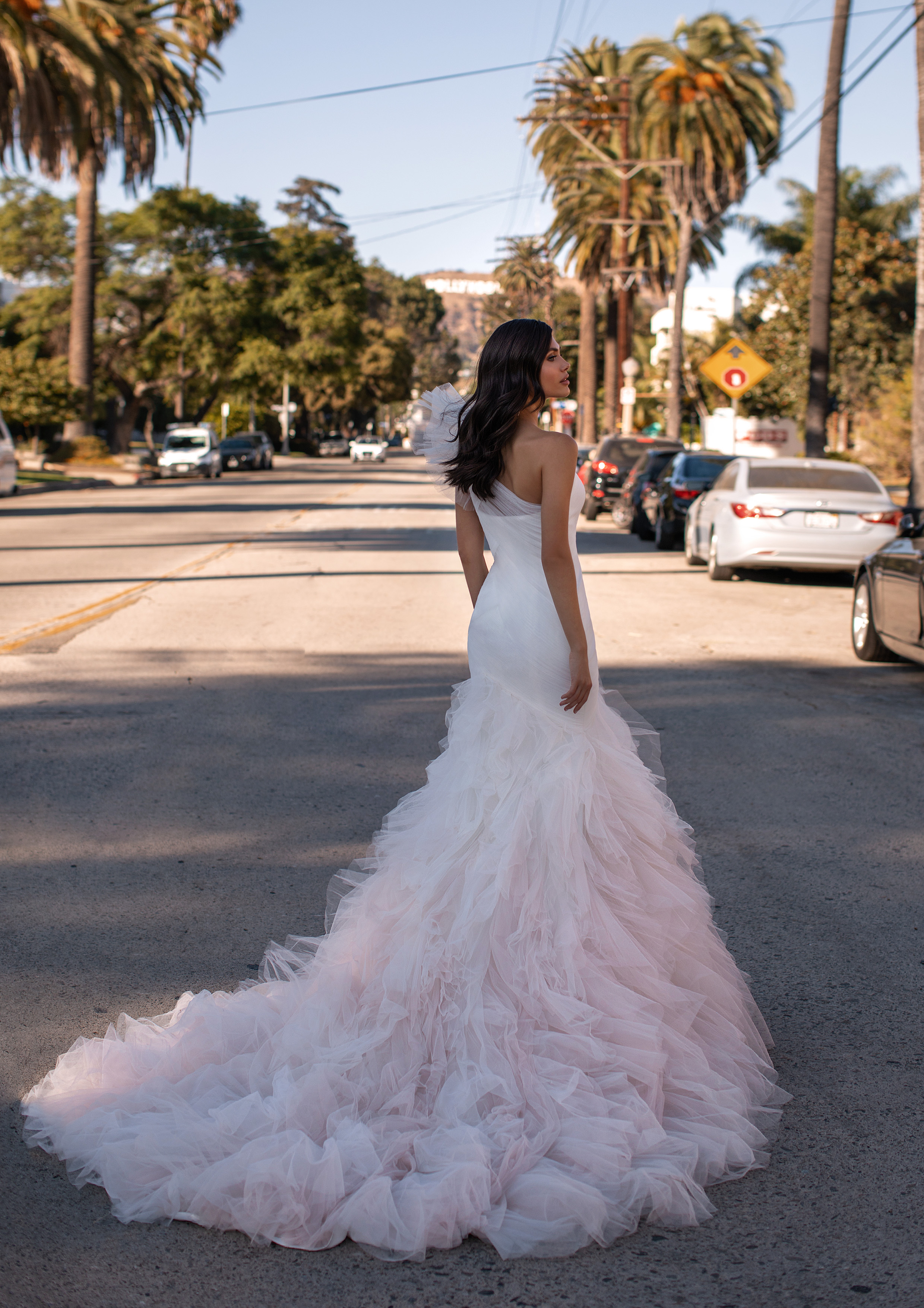 Um vestido de verdadeira estrela de cinema, com torso ajustado de tule drapeado, detalhe no ombro ultraglamouroso e uma saia rodada em tom rosado. | Modelo Neal de Pronovias 2021 Cruise Collection – Ashley Graham X Pronovias