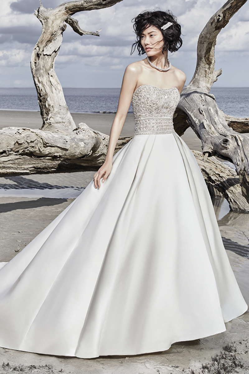Um vestido de noiva altamente elegante apresenta toques finais de cortar a respiração, este modelo de seda Carlo apresenta um corpete bordado e, ainda, cristais Swarovski. Decote em U sem alças. Terminado com botões de cristal que se arrastam desde o fecho até à bainha.
<a href="https://www.maggiesottero.com/sottero-and-midgley/phoenix/11561">Sottero and Midgley</a>