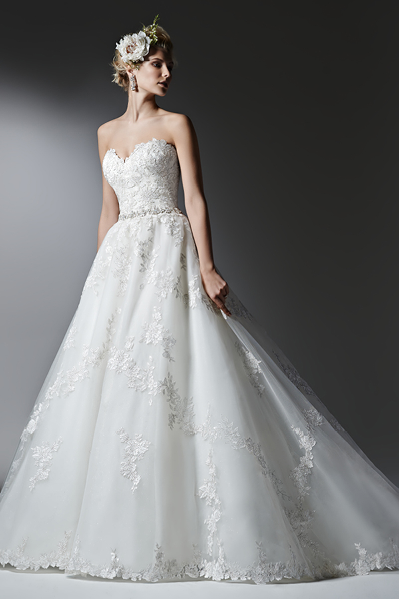 Uma renda romântica e várias camadas de tule brilhante dão origem a este vestido com efeito balão, realçado com cristais delicados Swarovski no cinto, apresentando um decote em forma de coração suave e reservado. Terminado com botões de cristal em vez do fecho e um espartilho interior.
<a href="https://www.maggiesottero.com/sottero-and-midgley/alandra/9571" target="_blank">Sottero and Midgley</a>