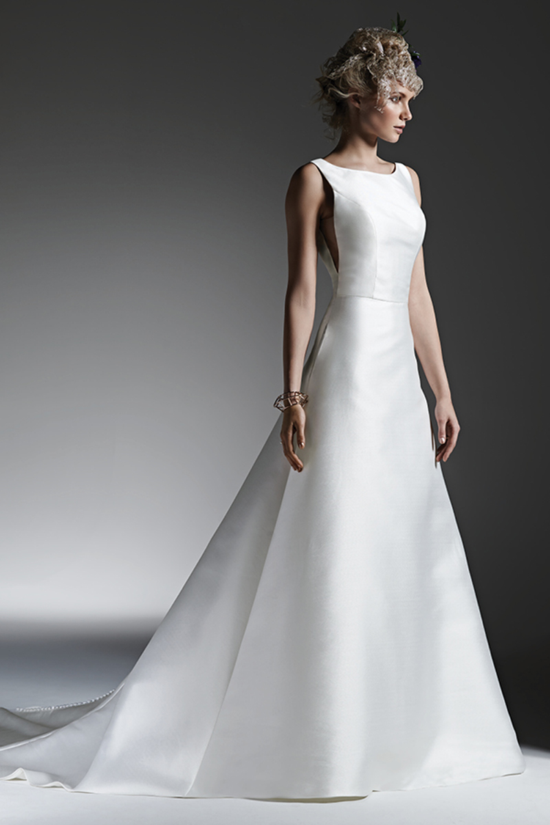 Mikada Luxe Reena cria este vestido Linha A com um decote barco bastante sofisiticado. Bolsos escondidos e costas abertas que conferem sensualidade ao look. Terminado com botões em vez do fecho.
<a href="https://www.maggiesottero.com/sottero-and-midgley/mccall/9592" target="_blank">Sottero and Midgley</a>