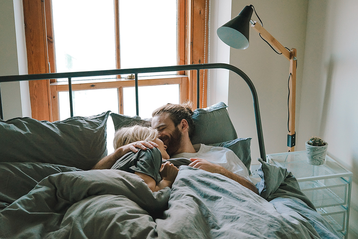 casal deitado na cama a beijar-se