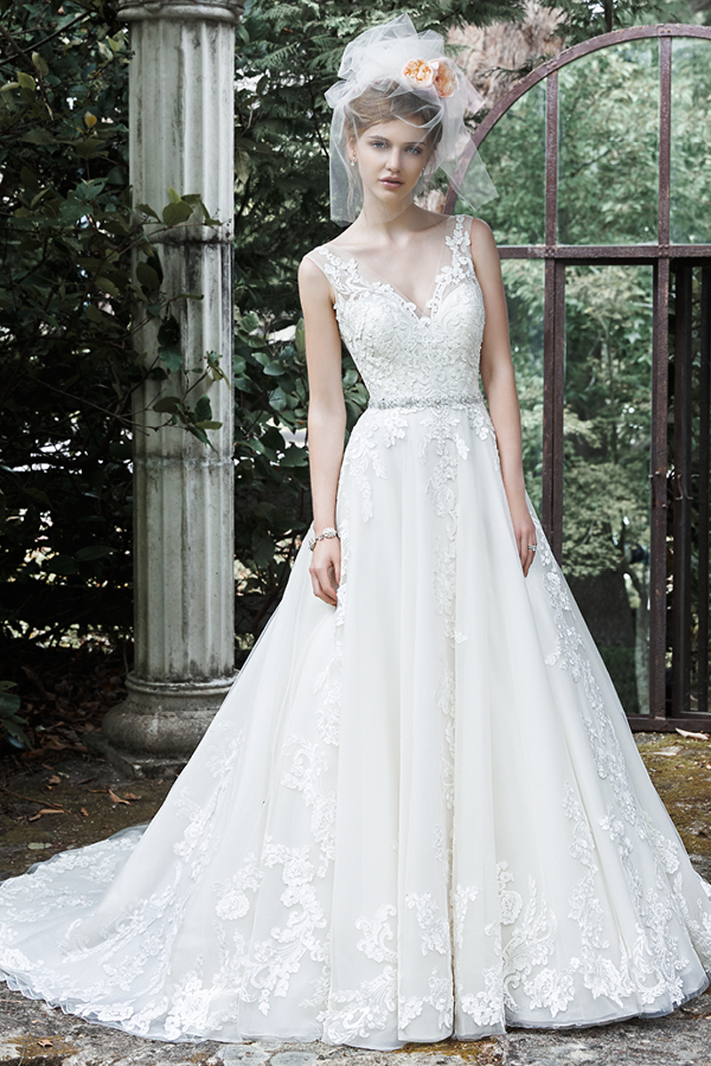 This exquisite ball gown wedding dress is complete with floral lace appliqués drifting down a tulle skirt, an elegant illusion V-neckline, and a glittering Swarovski crystal belt. Finished with plunging V-back and crystal buttons over zipper closure.
<a href="http://www.maggiesottero.com/dress.aspx?style=5MS701" target="_blank">Maggie Sottero</a>