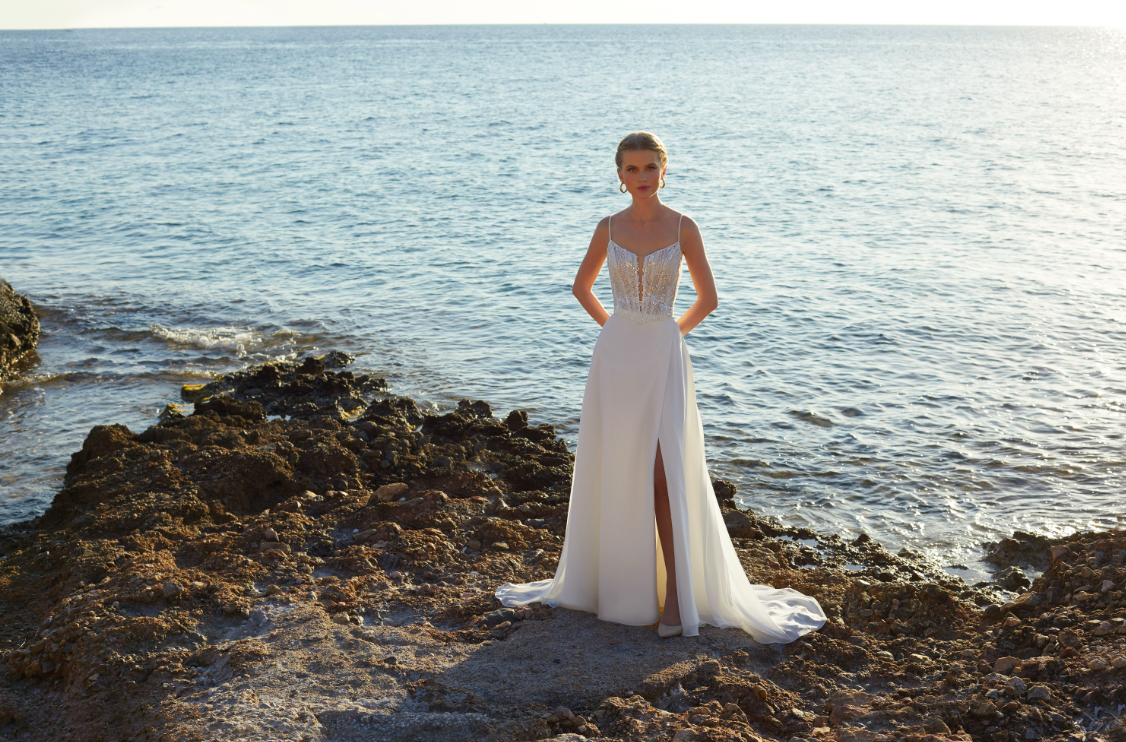 Modella sugli scogli indossa abiti Destination Romance con spacco profondo
