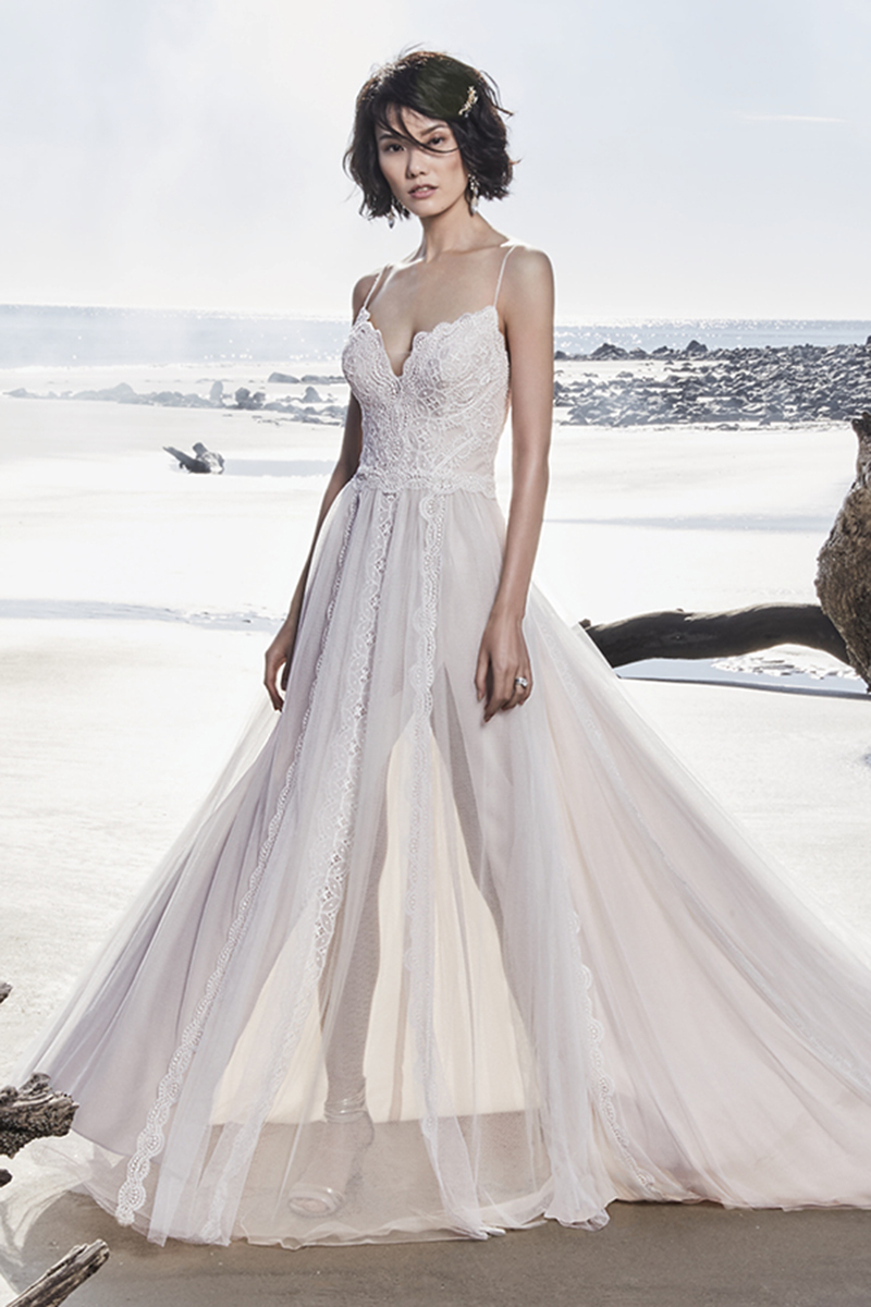 Este deslumbrante e romântico vestido de noiva apresenta uma renda fabulosa sobre um tule. Alças finas extremamente elegantes nascedm do decote em forma de coração e terminam numas costas de ilusão, realçadas por pormenores de renda. Terminado com botões de cristal sobre o fecho.
<a href="https://www.maggiesottero.com/sottero-and-midgley/olson/11560">Sottero and Midgley</a>