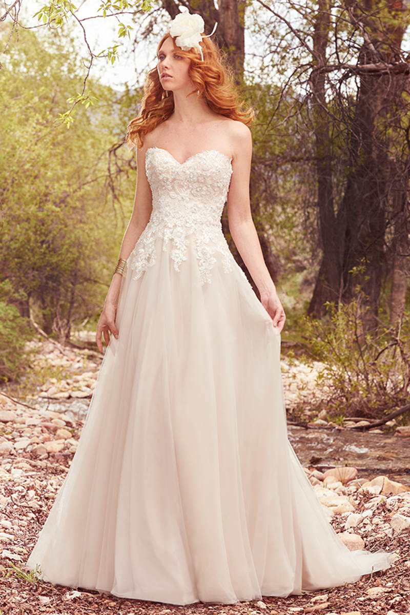 Pormenores de renda, perólas delicadas e detalhes brilhantes que decoram elegantemente o corpete deste vestido com Linha-A, sem alças e um decote em formato de coração. Um cinto removível está incluido.
<a href="https://www.maggiesottero.com/maggie-sottero/harmony/10103?utm_source=mywedding.com&utm_campaign=spring17&utm_medium=gallery" target="_blank">Maggie Sottero</a>