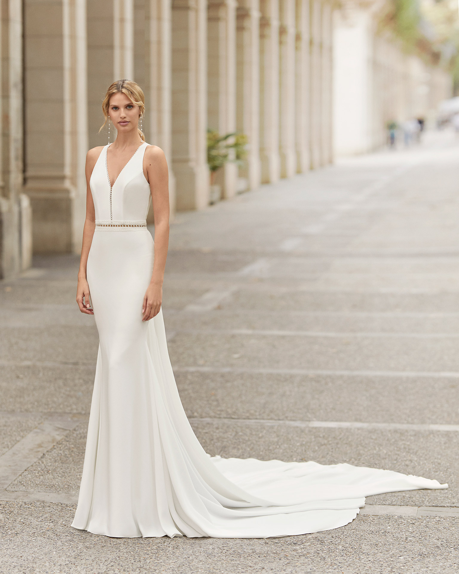 O romântico vestido Tailandia exala a beleza natural do corpo. De crepe liso suave e corte reto, exibe um decote em V, alças largas e costas abertas em forma de lágrima. Com cauda desmontável, é ideal para casar no verão, em frente ao mar. | Rosa Clará 2021