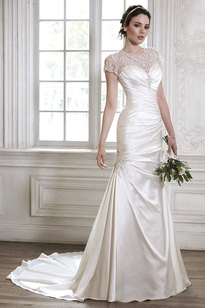 Vestido de noiva elegante, com decote cai-cai em forma de coração e enfeites de cristal Swarovski na gola e na cintura. Disponível com casaco de manga curta enfeitada também com cristais. Acabamento com botões de cristal sobre o zipper e o espartilho interior.
<a href="http://www.maggiesottero.com/dress.aspx?style=5MS131" target="_blank">Maggie Sottero Spring 2015</a>