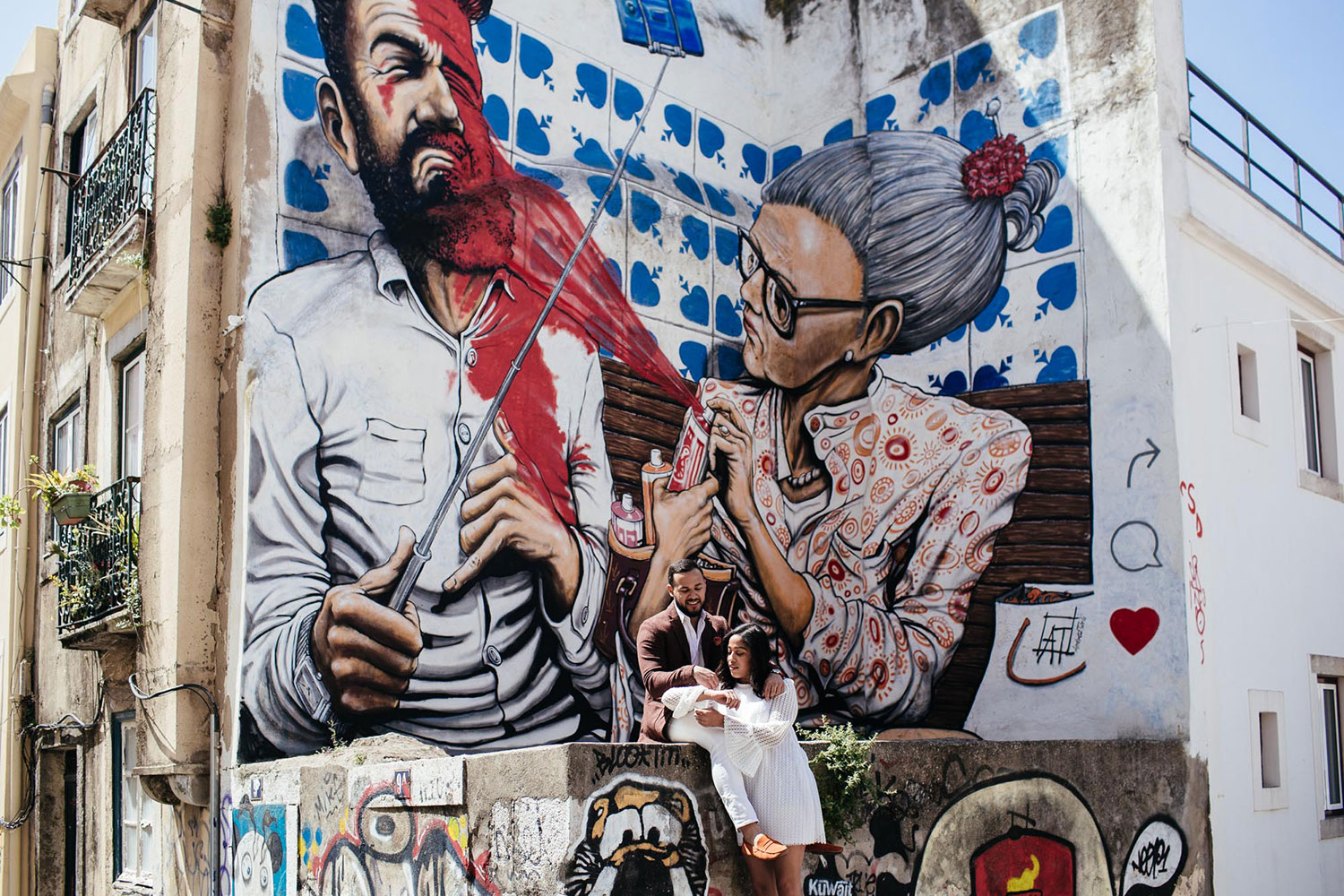 casal sentado em frente a uma parede com grafiti artístico mural arte de rua
