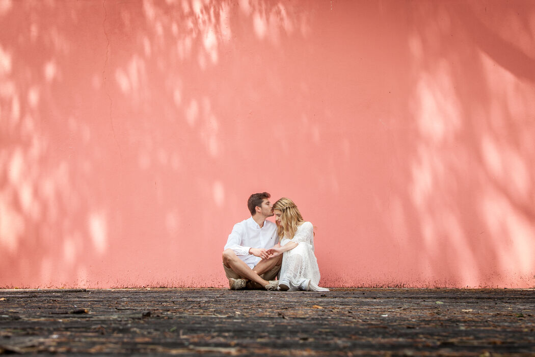 casal sentado no chão parede rosa