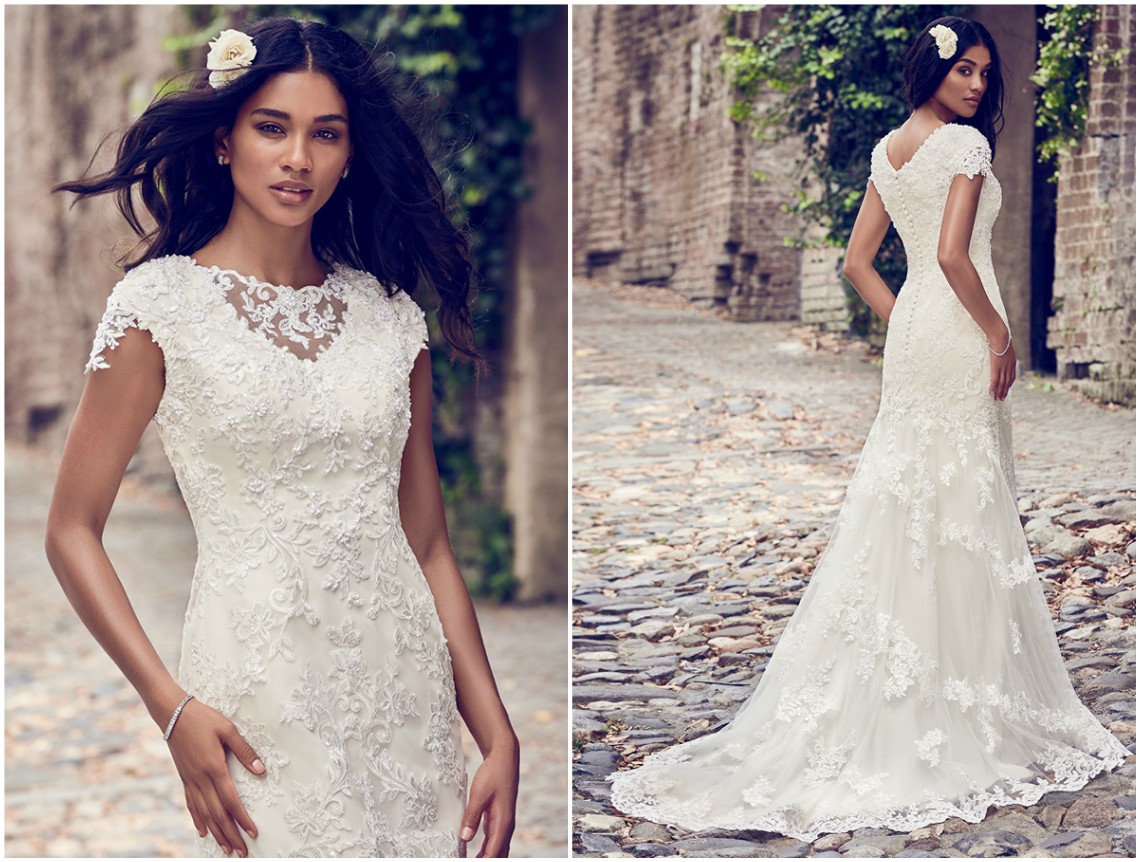 Um clássico fit-and-flare vestido de noiva, com aplicações de renda que caem sobre tule em cascata e que acentuam o decote barco e as mangas curtas. Acabamentos com botões forrados sobre fecho zíper. <a href="https://www.maggiesottero.com/maggie-sottero/stacey/11193?utm_source=zankyou&utm_medium=gowngallery" target="_blank">Maggie Sottero</a>