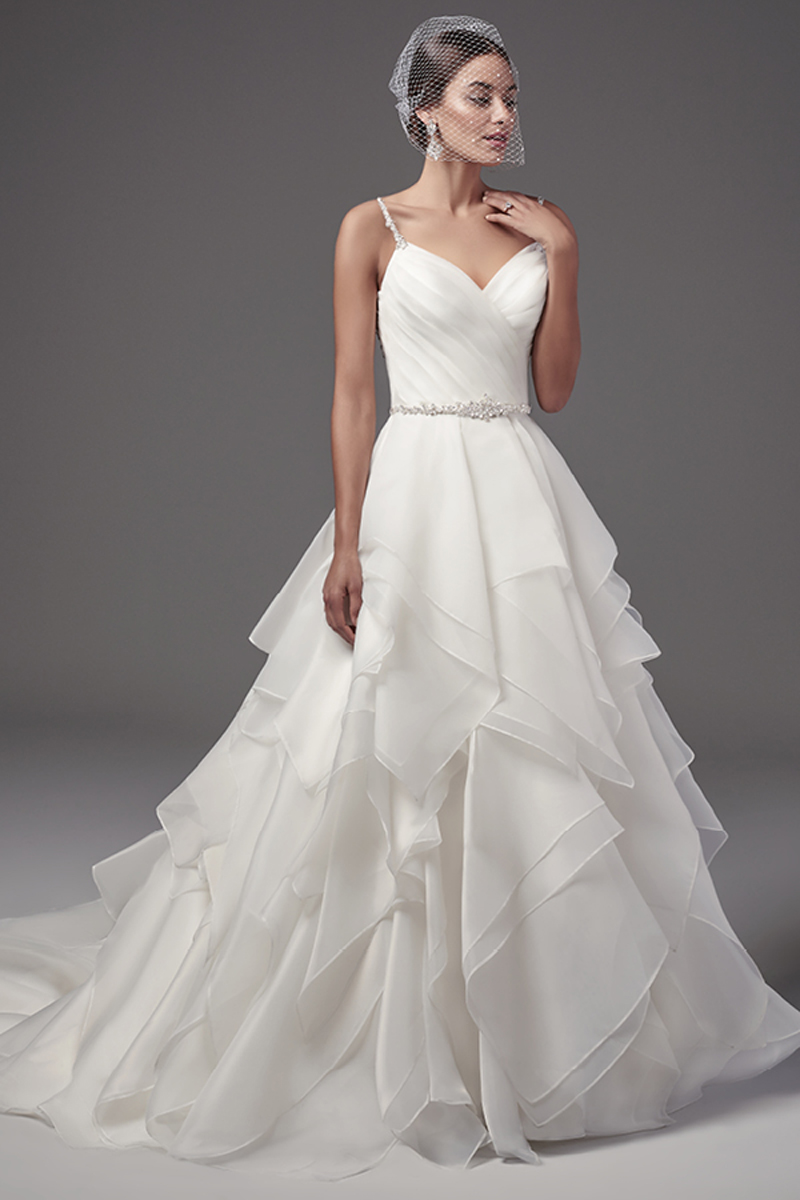 Este elegante vestido com efeito balão apresenta um corpete que termina em folhos com várias camadas de organza Marquice. Cristais Swarovski e contas que decoram detalhadamente as costas e a linha da cintura. Terminado com um decote em forma de coração, botões com cristas e um fecho.
<a href="https://www.maggiesottero.com/sottero-and-midgley/blaire/10209?utm_source=mywedding.com&utm_campaign=spring17&utm_medium=gallery" target="_blank">Sottero and Midgley</a>