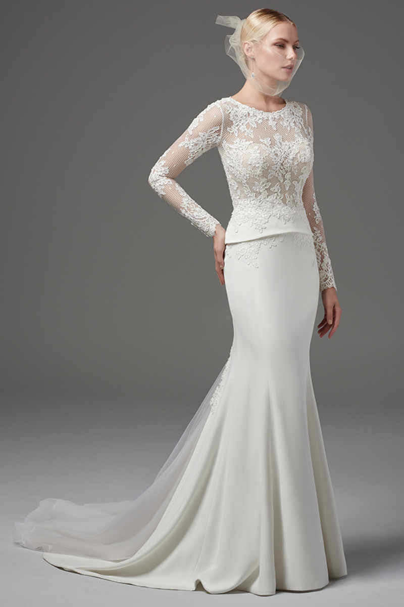 Sofisticado, mas sexy. Este vestido fit-and-flare Yolina Crepe com mangas compridas apresenta um corpete com um decote em forma de coração. Tudo isto com pormenores em renda. Terminado com botões em vez do fecho.
<a href="https://www.maggiesottero.com/sottero-and-midgley/harlow/10230?utm_source=mywedding.com&utm_campaign=spring17&utm_medium=gallery" target="_blank">Sottero and Midlgey</a>