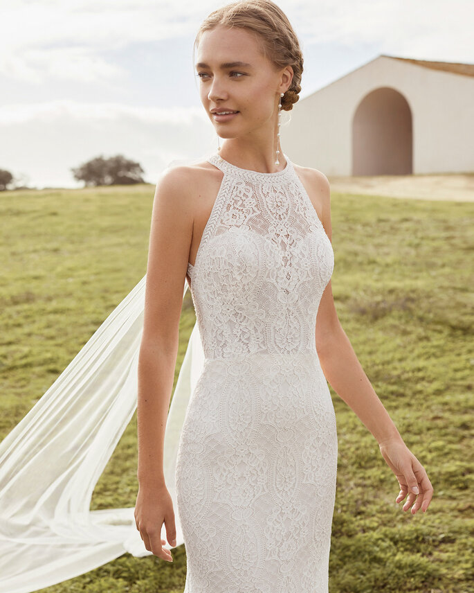 O vestido de noiva Aura exibe uma silhueta de sereia, com um toque sexy e sofisticado, perfeito para um casamento civil mágico, sobretudo na primavera. O encanto exala do corpete, através de uma imponente renda e decote halter, que se destaca por costas completamente aberta com uma capa removível. | Rosa Clará Boheme 2021