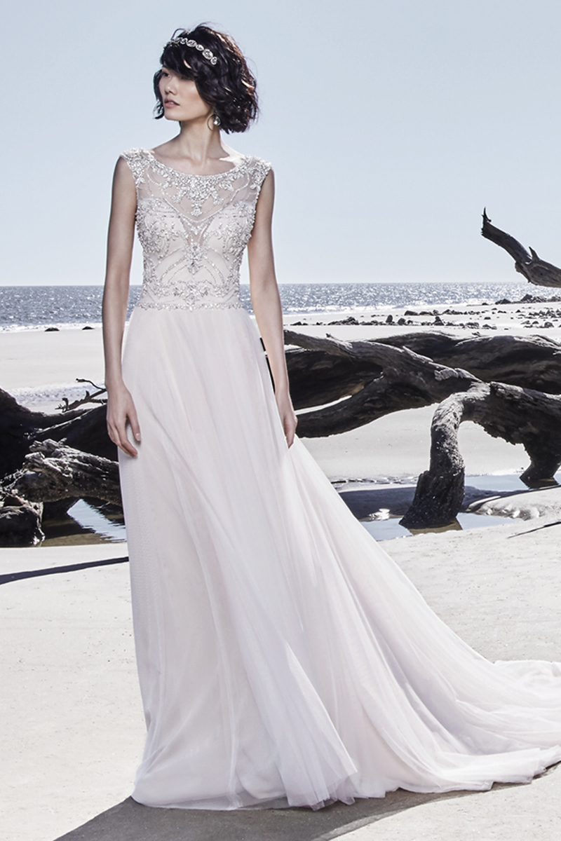 Um vestido de noiva com detalhes bordados, assim como cristais Swarovski que dançam ao longo do corpete linha-A. Decote em forma de coração, mangas curtas e um decote em U nas costas. Uma saia de tule extremamente chic que busca inspiração no estilo mais vintage. Terminado com botões de cristal que cobrem o fecho.
<a href="https://www.maggiesottero.com/sottero-and-midgley/ezra/11533">Sottero and Midgley</a>