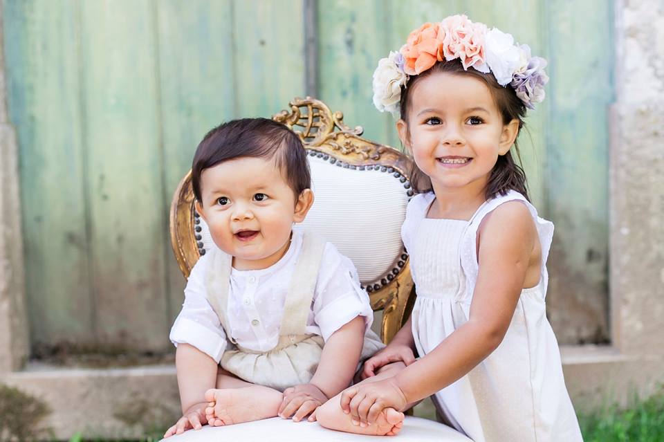 menino bebé e menina com coroa de flores vestidos de festa