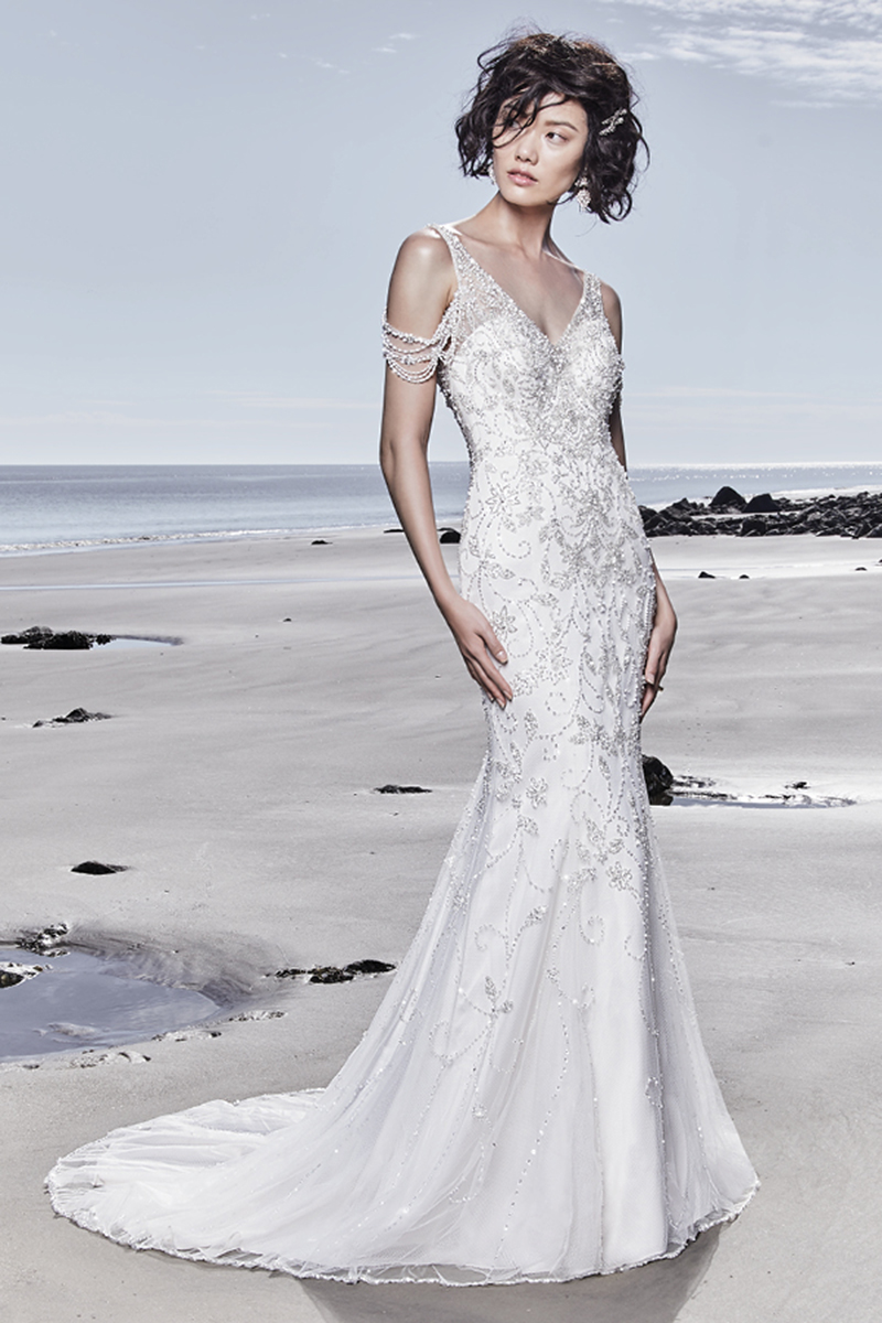 Um vestido de noiva caracterizado pelo glamour e sofisticação. Apresenta cristais Swarovski ao longo do tule. Para além disso, exibe, também, mangas, decote em V e um decote nas costas em forma de U. Terminado com botões de cristal que cobrem o fecho.
<a href="https://www.maggiesottero.com/sottero-and-midgley/georgina/11535">Sottero and Midgley</a>