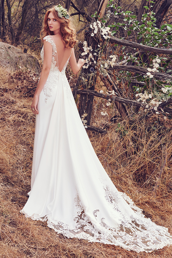 Este look romântico com baínha Olrando Satin apresenta detalhes em renda realçados pelas contas e cristais Swarovski ao longo do corpete. Ilusão em V no decote em forma de coração, mangas e costas abertas em V. Terminado com fecho.