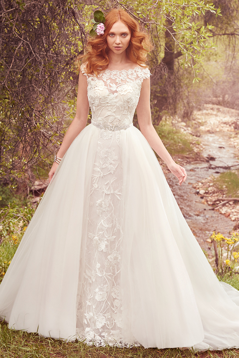 Uma impressionante vestido de renda que realça as pérolas e cai em efeito cascata ao longo do seu adorável fit-and-flare, decote barco e mangas curtas. Com um toque de extravagância, este vestido termina com botões na zona de fechar. Um tule removível na saia (vendido separadamente) confere volume e a extravagância a este look. O cinto com um laço é tmabém vendido separadamente.
<a href="https://www.maggiesottero.com/maggie-sottero/gretchen/10100?utm_source=mywedding.com&utm_campaign=spring17&utm_medium=gallery" target="_blank">Maggie Sottero</a>