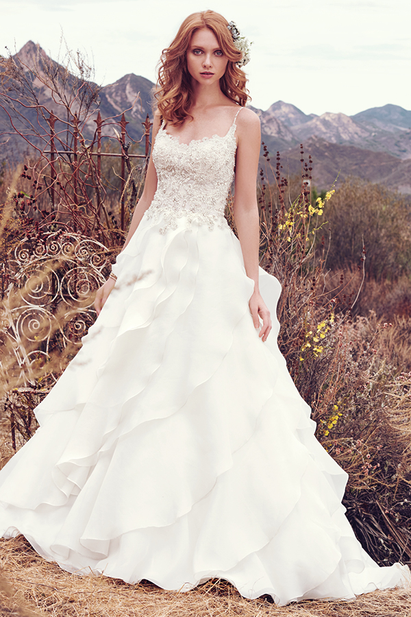 Este vestido de noiva maravilhoso apresenta um corpete de renda bordado decorado com cristas Swarovski e, ainda, alças finas, decote em forma de U e ilusão em forma de V nas costas. Uma saiade Celia organza assimétrica complete este look fabuloso. Terminado com botões de cristais na zona do fecho.