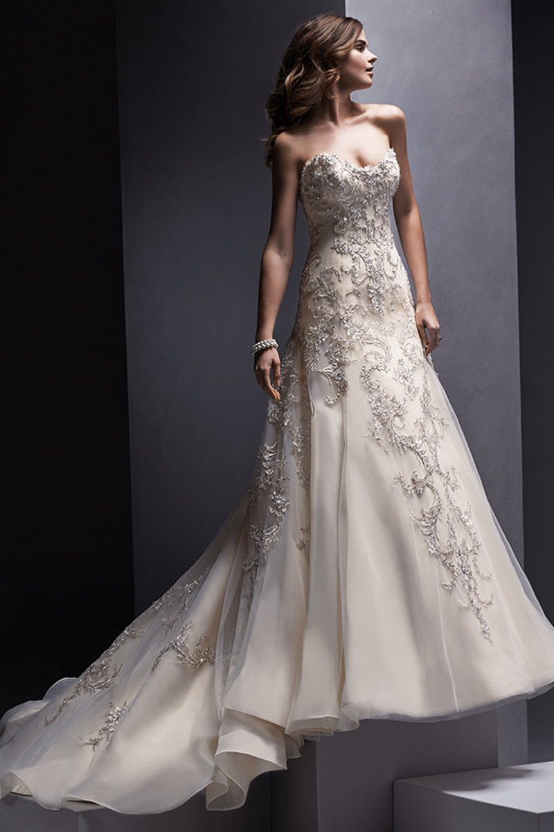 Um vestido linha-A com pormenores de renda reluzentes. Sem alças e com um decote em forma de coração. Terminado com botões em vez do fecho e espartilho interior.
<a href="http://www.sotteroandmidgley.com/dress.aspx?style=5SR133&page=0&pageSize=36&keywordText=&keywordType=All" target="_blank">Sottero and Midgley</a>