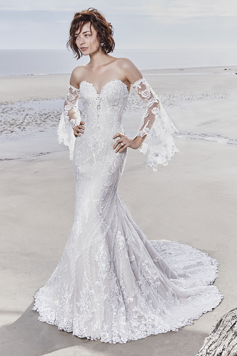 Chique e sexy, este vestido de noiva descontraído fit-and-falre apresenta detalhes de rendas geométricas sobre o tule. Os motivos de renda decoram o decote ilusão, quer frontal como o das costas. Termina com botões de cristal e fecho. Mangas abertas de renda vendidas separadamente.
<a href="https://www.maggiesottero.com/sottero-and-midgley/kingsley/11546">Sottero and Midgley</a>