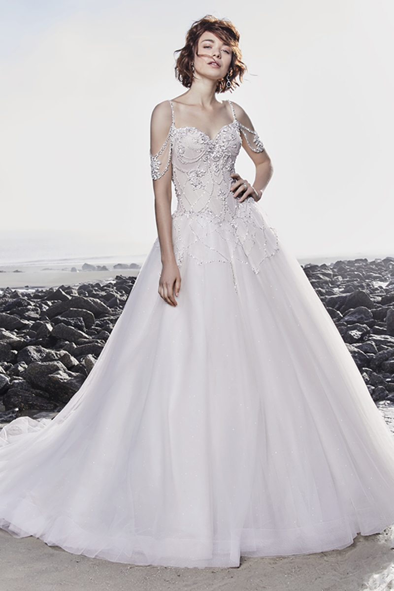 Este maravilhoso vestido de noiva apresenta um brilhante corpete de tule, realçado pelos seus padrões bordados que terminam numa saia volumosa de tule. Alças finas surgem de um decote em V, extremamente sexy. Terminado com botões de cristais que cobrem o fecho.
<a href="https://www.maggiesottero.com/sottero-and-midgley/boston/11519">Sottero and Midgley</a>