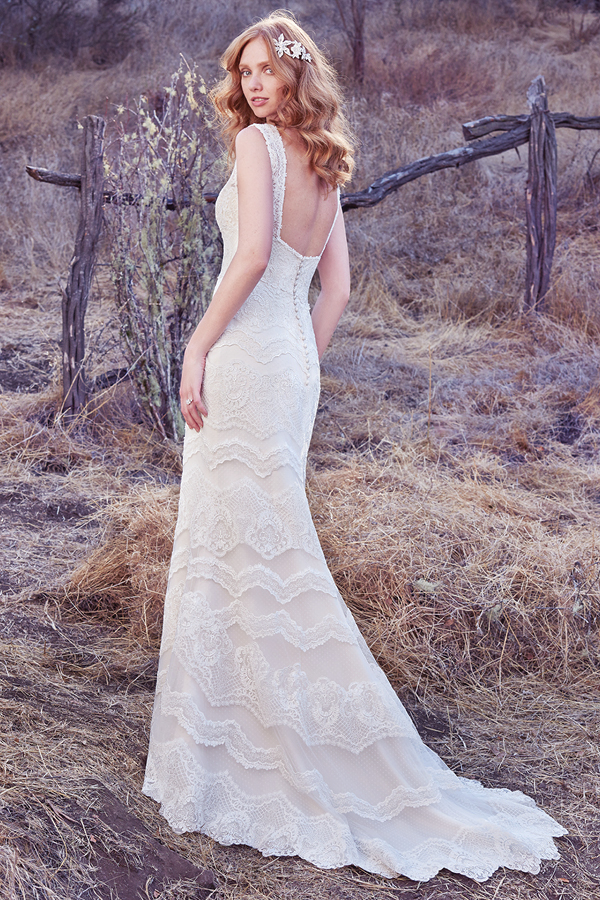 Inspirado em estilos mais chic e boho, este vestido apresenta detalhes de renda horizontais. Uma renda pura constituem as alças deste vestido, completando, desta forma, o decote em V e o a forma de quadrado nas costas. Terminado com botões cobertos na área do fecho. completing the V-neckline and square back. Finished with covered buttons over zipper closure. Chic and boho-inspired, this sheath gown features horizontal lace motifs. Sheer lace and side insets comprise the gown’s straps,
completing the V-neckline and square back. Finished with covered buttons over zipper closure.