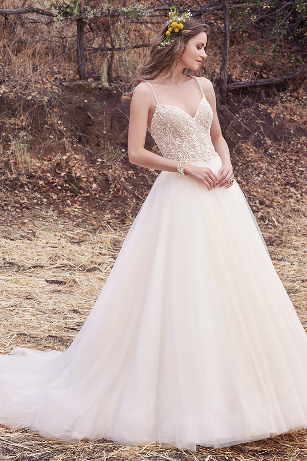 Este vestido de noiva encantador apresenta um corpete cuja beleza é realçada com bordados sobre uma volumosa saia de tule. Alças finas deslizam desde o decote em forma de coração até a um decote em forma de U nas costas. Terminado com botões de cristal na zona do fecho.