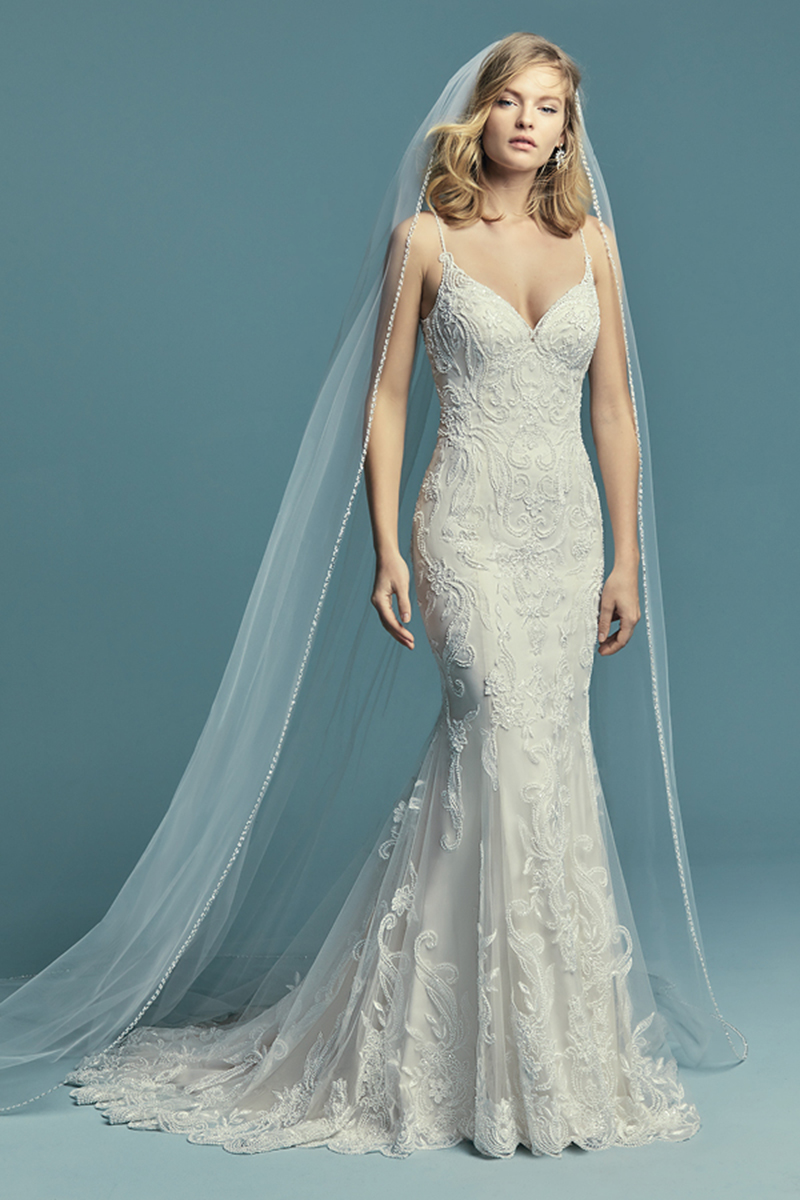 <a href="https://www.maggiesottero.com/maggie-sottero/jolynn/11487">Maggie Sottero</a>
Pormenores de renda caem ao longo do tule que dá origem a este magnífico vestido de noiva fit-and-flare. Alças finas surgem desde o decote em forma de coração e efeito ilusão nas suas costas. Terminado com botões cobertos sobre um fecho.