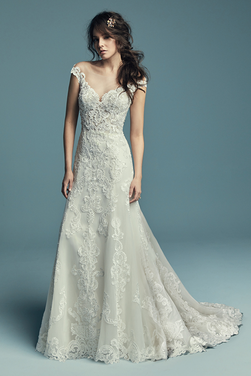 <a href="https://www.maggiesottero.com/maggie-sottero/serena/11431">Maggie Sottero</a>
Pormenores de renda caem em cascata ao longo do tule que confeciona este vestido de noiva off-the-shoulder com corte linha-A. Terminado com botões cobertos sobre um fecho.