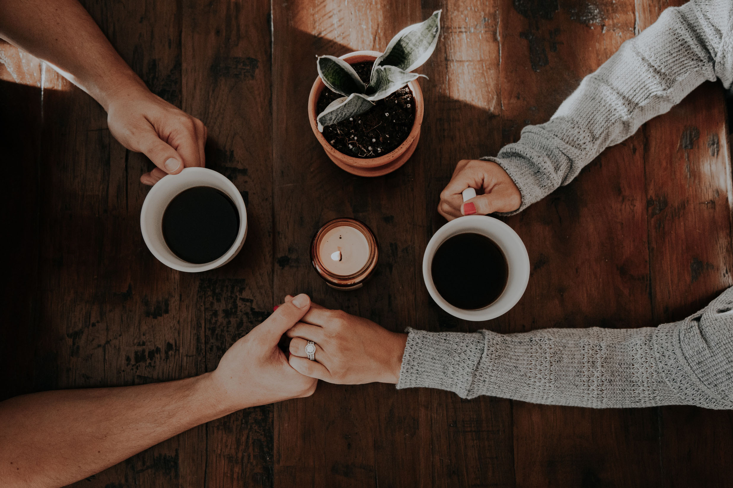 casal a beber café de mãos dadas