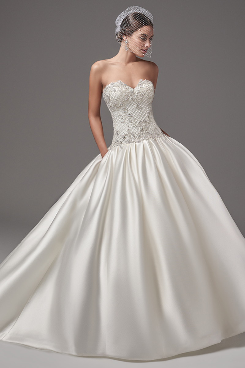 Este vestido Yaron Mikado com efeito balão rico em glamour apresenta um corpete com decote em forma de coração com bordados cruzados e pérolas brilhantes. Um saia plissada com bolsos descaídos na cintura oferecem dimensão e brilho. Terminado com botões de pérolas em vez do fecho e um espartilho interior.
<a href="https://www.maggiesottero.com/sottero-and-midgley/hampton/10229?utm_source=mywedding.com&utm_campaign=spring17&utm_medium=gallery" target="_blank">Sottero and Midgley</a>
