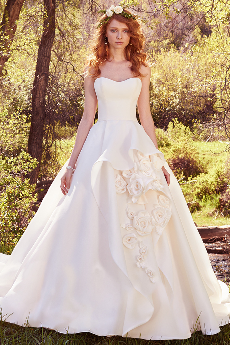 Confeccionado com organza Shavon, este vestido simples mas no entanto com um impressionante efeito balão complementa-se com rosas feitas à mão realçadas com pérolas. Um vestido sem alças com um efeito muito fluído evoca um toque romântico chic.
<a href="https://www.maggiesottero.com/maggie-sottero/bianca/10088?utm_source=mywedding.com&utm_campaign=spring17&utm_medium=gallery" target="_blank">Maggie Sottero</a>