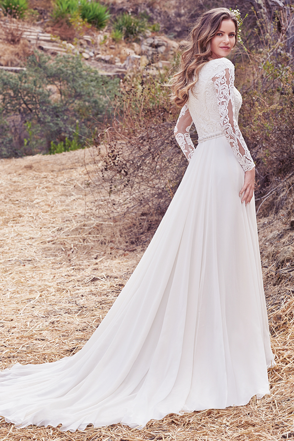 Este vestido linha-A apresenta um corpete em renda e mangas até aos cotovelos com efeito ilusão, assim como o seu decote em forma de U. Um cinto com cristais Swarovski e um decote em V nas costas confere um toque de romance surpreendente. Terminado com botões.