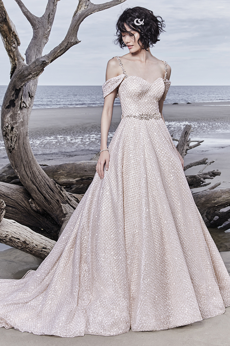 Um único e maravilhoso upgrade para todos os vestidos de noiva princesa, este deslumbrante modelo apresenta um tule com padrão cruzado sobre um tule de lantejoulas. Decote em forma de coração e apresenta, ainda, um cinto que exibe cristais Swarovski. Terminado com um corpete interior e botões.
<a href="https://www.maggiesottero.com/sottero-and-midgley/magdalyn/11551">Sottero and Midgley</a>