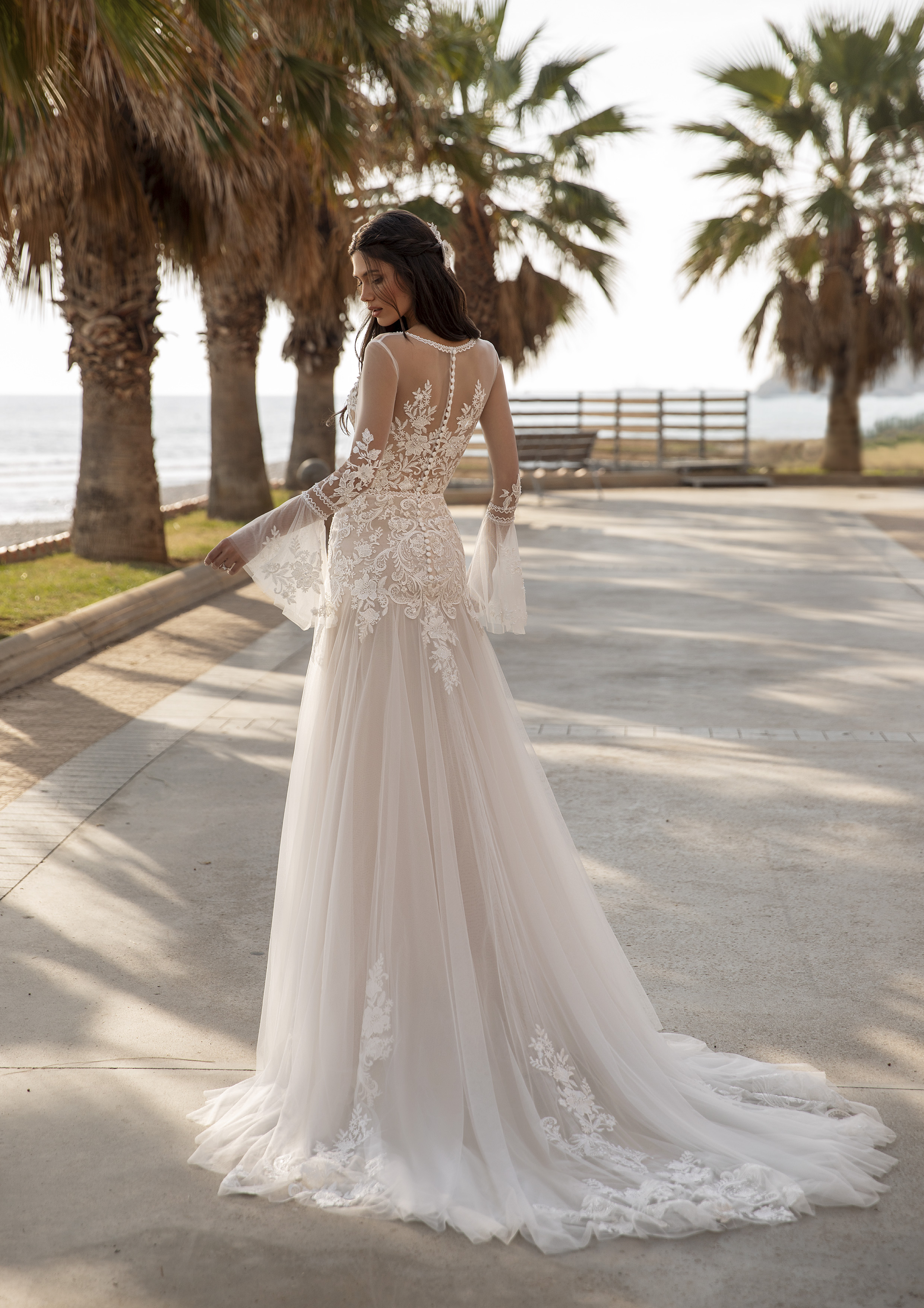 Vestido de noiva estilizado com renda e tule, com mangas sino compridas, saia evasé com abertura e uma cauda estilo capela. | Modelo Tyson da Pronovias 2021 Cruise Collection