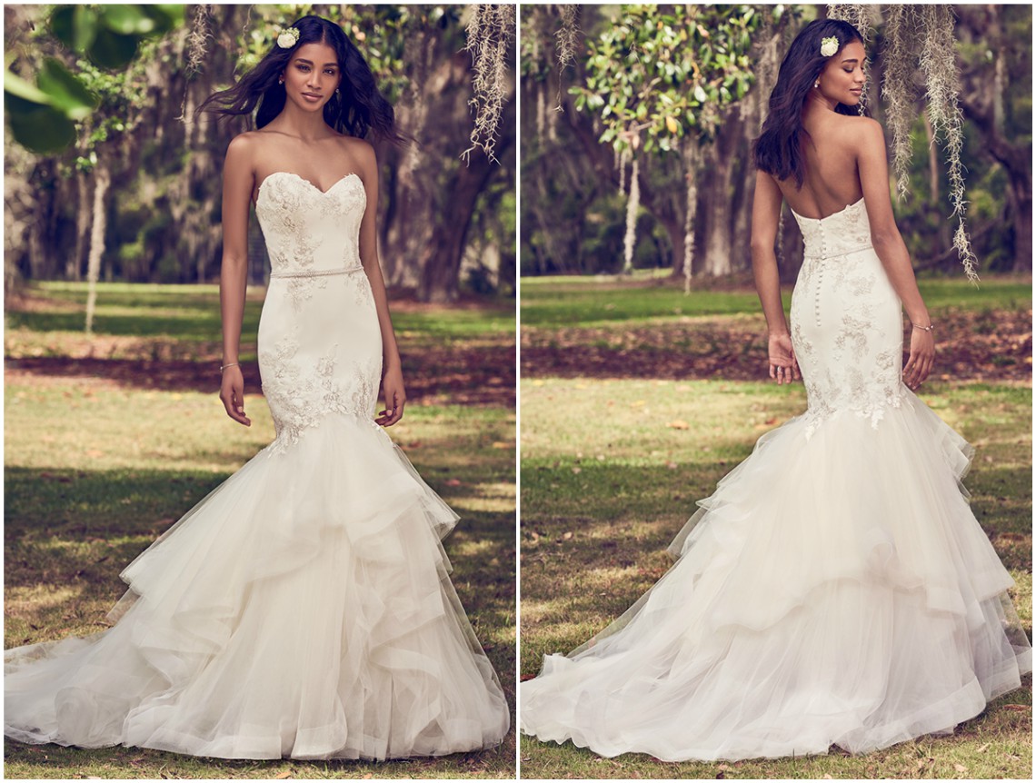Vestido corte sereia com corpete em tule, adornado com intricados bordados florais que se estendem à saia de tule, que abre em crina. Completo com decote coração cai-cai e um cinto com pérolas e demais pedrarias. Acabamentos com botões forrados sobre fecho zíper. <a href="https://www.maggiesottero.com/maggie-sottero/dalinda/11166?utm_source=zankyou&utm_medium=gowngallery" target="_blank">Maggie Sottero</a>