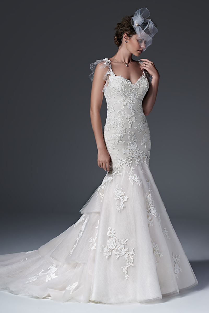 Um modelo fit-and-flare chic de renda com um padrão floral. Decote em forma de coração e botões de pérolas em vez de um fecho.
<a href="https://www.maggiesottero.com/sottero-and-midgley/elizabeth/9557" target="_blank">Sottero and Midgley</a>