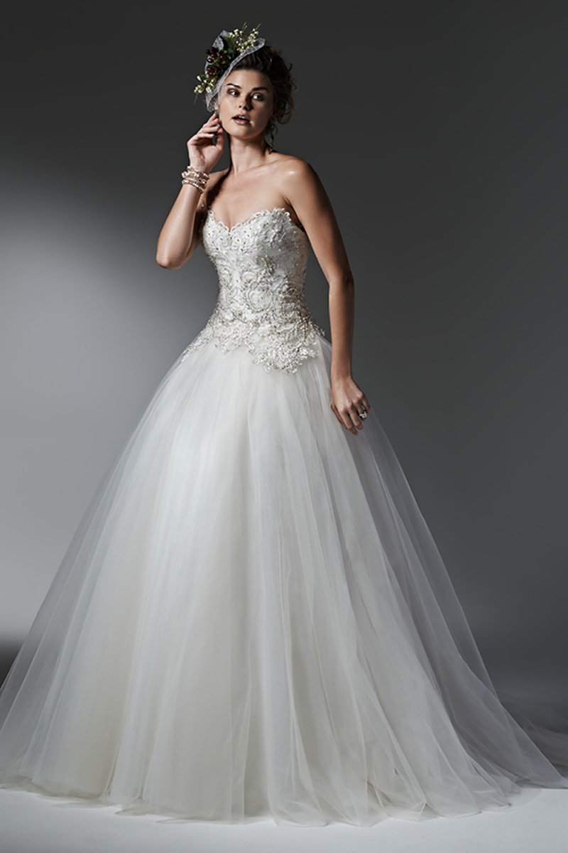 Camadas leves de tule que criam esta bonita saia deste impressionante vestido de noiva com efeito balão, apresentando cristais Swarovski que oferecem destaque ao corpete. Decote em forma de coração. Terminado com botões de pérolas em vez de um fecho.
<a href="https://www.maggiesottero.com/sottero-and-midgley/sigourney/9560" target="_blank">Sottero and Midgley</a>