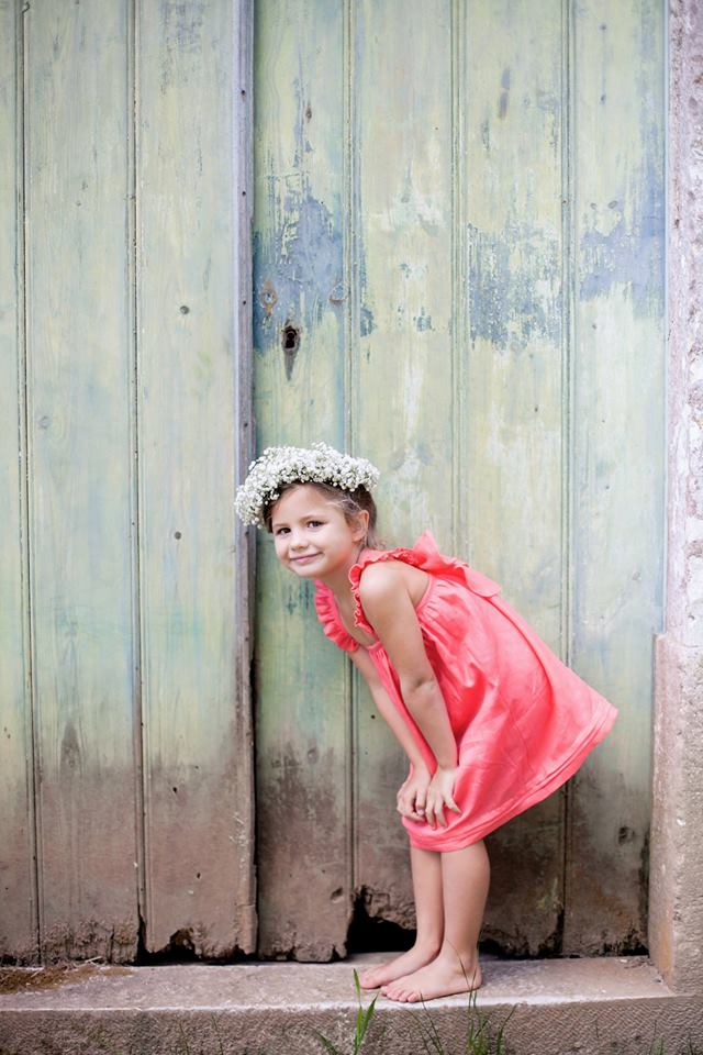 menina com vestido cor de rosas de alças e coroa de flores