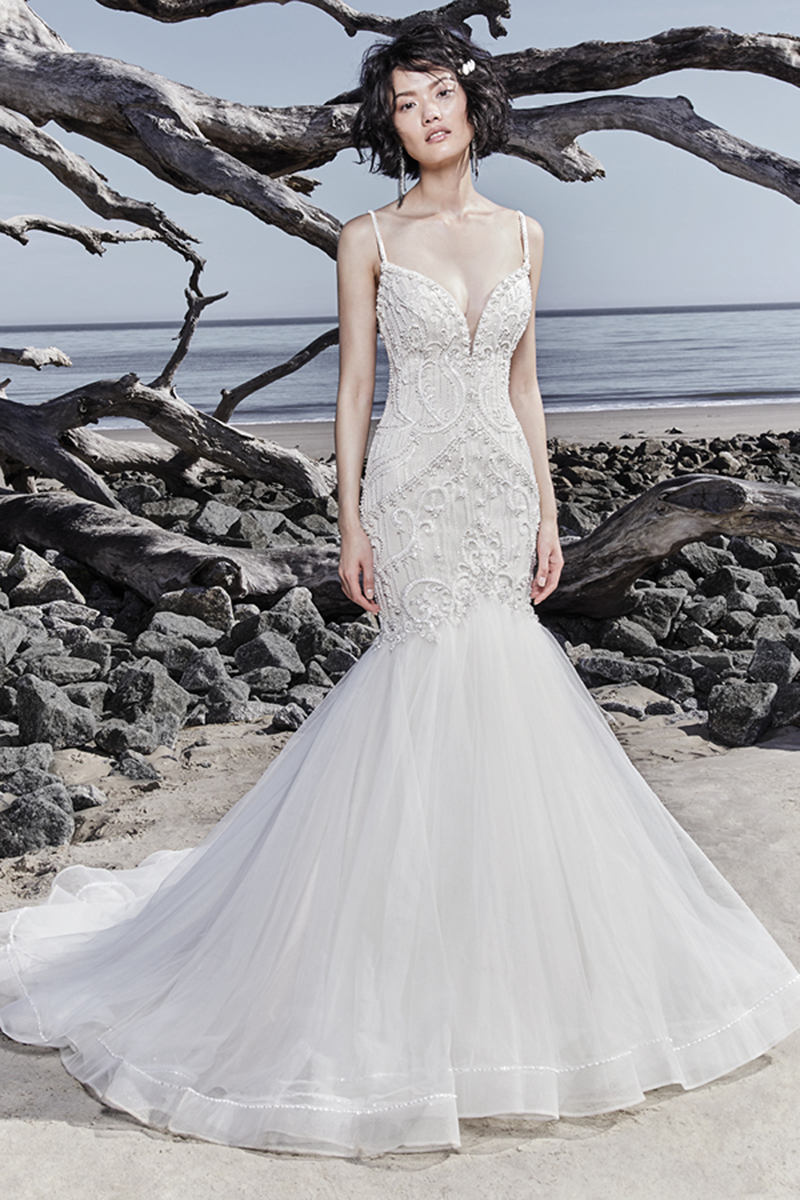 Brilhantes pormenores de renda e cristais Swarovski adornam o corpete deste sexy vestido de noiva fit-and-flare, completado por um decote em forma de coração de ilusão, alças finas e um decote em U nas costas. Terminado com botões.
<a href="https://www.maggiesottero.com/sottero-and-midgley/nouvelle/11559">Sottero and Midgley</a>