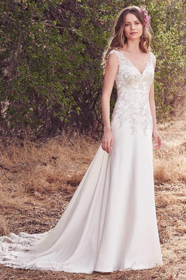 Este look romântico com baínha Olrando Satin apresenta detalhes em renda realçados pelas contas e cristais Swarovski ao longo do corpete. Ilusão em V no decote em forma de coração, mangas e costas abertas em V. Terminado com fecho.