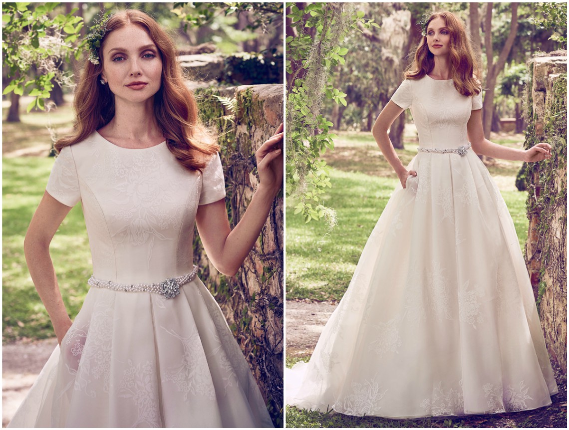 Doce e elegante vestido de noiva em organza, com um print floral inovador. Decote redondo, manga curta e bolsos laterais completam o etéreo romance deste modelo. Acabamentos com botões em pérola sobre fecho zíper e fecho interior elástico. O cinto de pérolas e cristais Swarovski é vendido à parte. <a href="https://www.maggiesottero.com/maggie-sottero/dylan-marie/11168?utm_source=zankyou&utm_medium=gowngallery" target="_blank">Maggie Sottero</a>