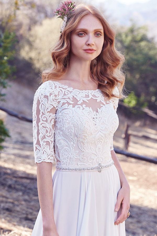 Este vestido linha-A apresenta um corpete em renda e mangas até aos cotovelos com efeito ilusão, assim como o seu decote em forma de U. Um cinto com cristais Swarovski e um decote em V nas costas confere um toque de romance surpreendente. Terminado com botões.